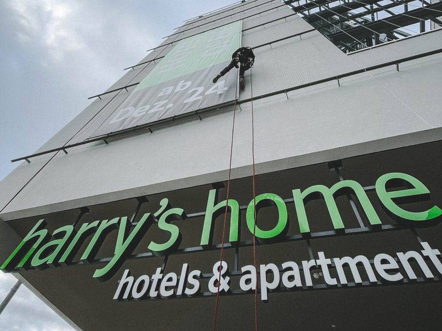 Monteur bei der Montage einer Werbeplane für ein Harrys Home Hotel.